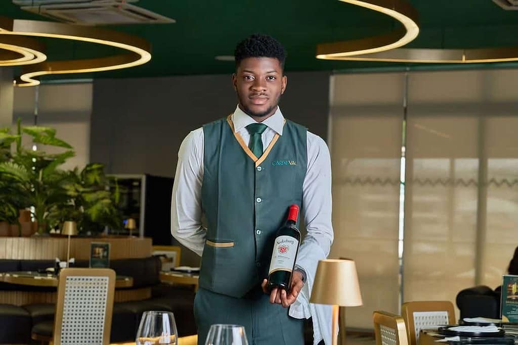 A waiter servicing wine at Carneval restaurants