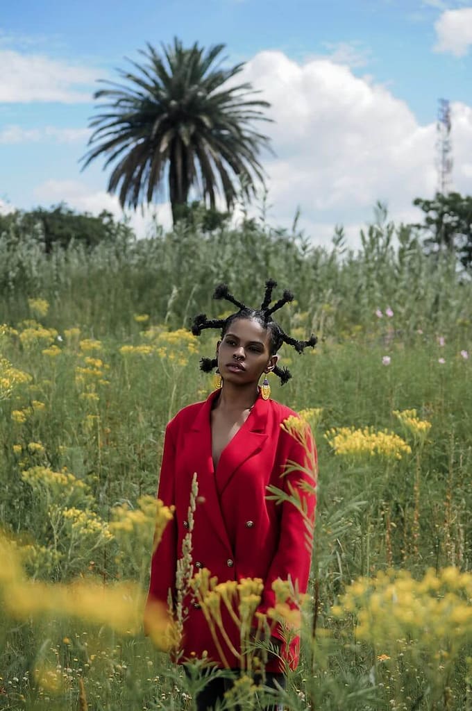 young woman in red coat standing in tropical meadow