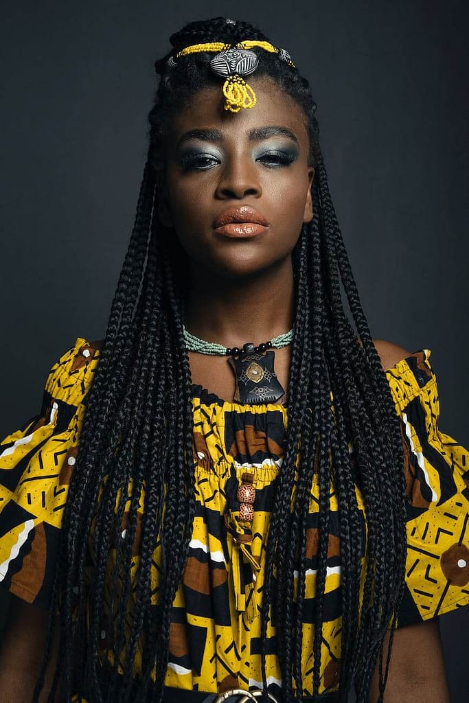 attractive woman with african pigtails hairstyle in yellow dress with exotic pattern