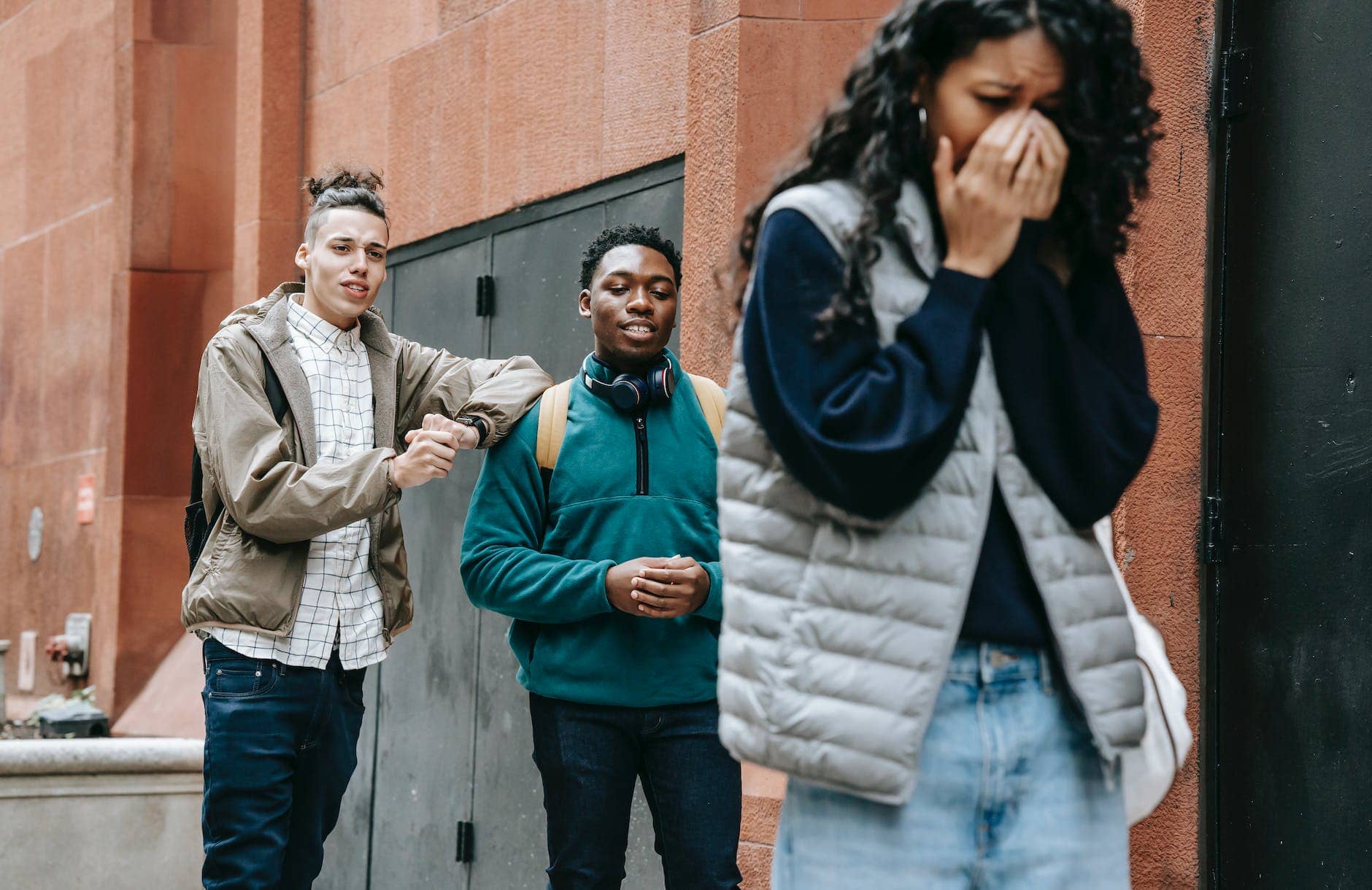 diverse young men bullying crying ethnic lady