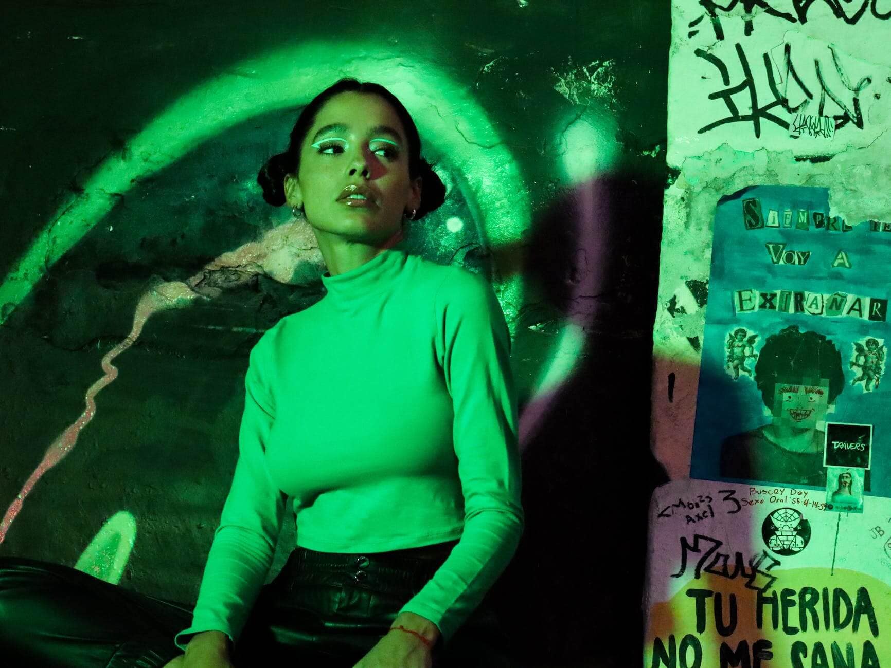 woman in white long sleeves sitting beside the ugly wall